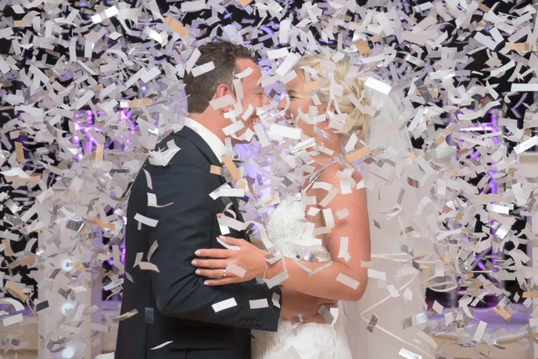 Bride and groom's first dance at wedding reception. The air is filled with confetti fired from a cannon.