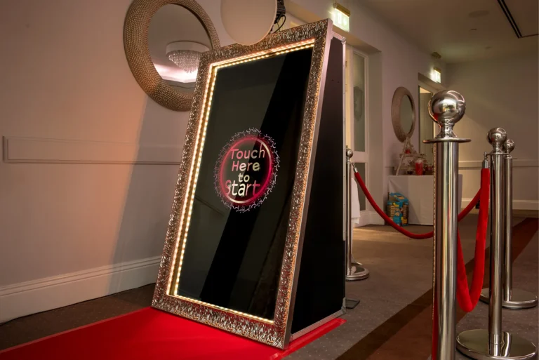 Photo booth magic mirror with red carpet and rope barriers at wedding reception.