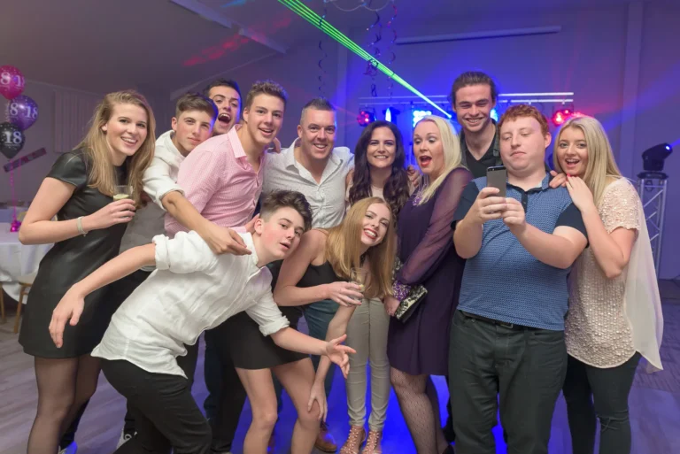 Family having fun and posing for camera at birthday party. Laser light show from mobile disco in the background.