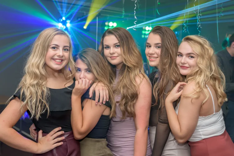 Young women smiling for picture at 18th Birthday party. Mobile Disco light show in the background.